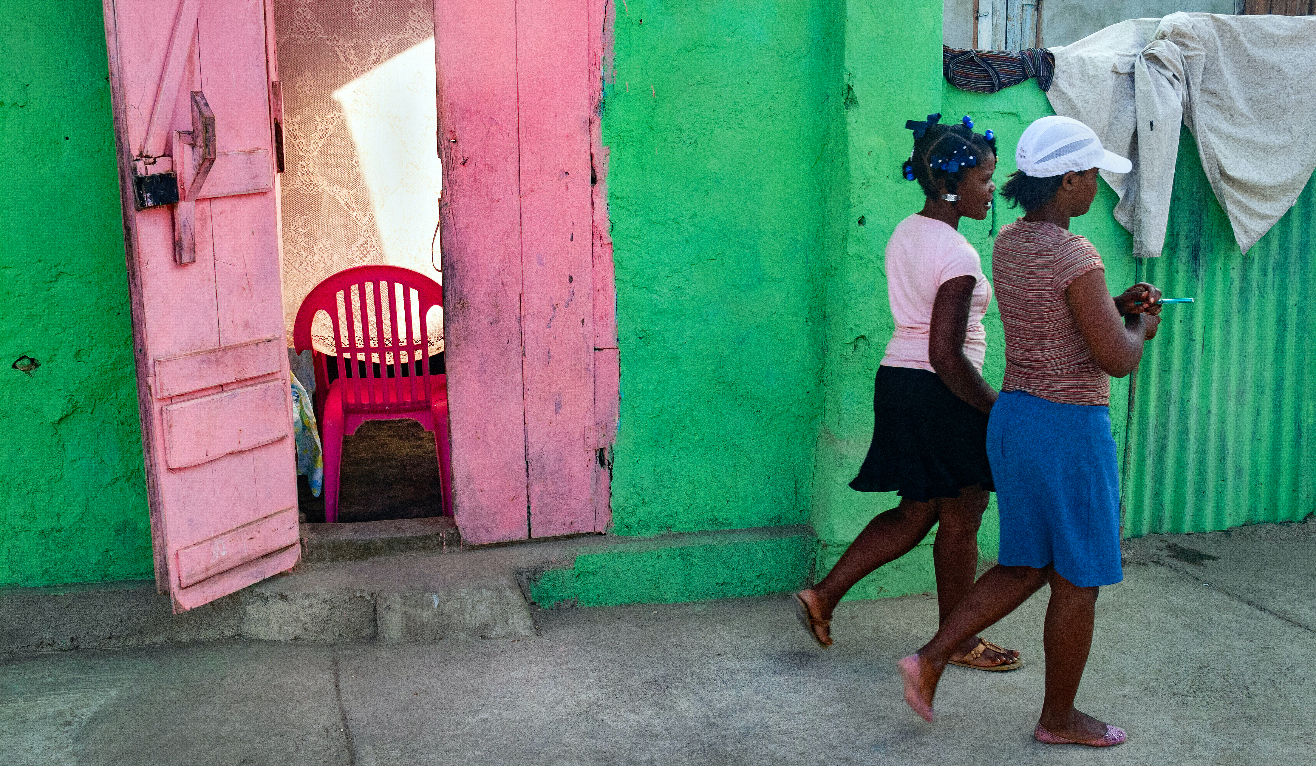 Two young Haitian women walk along the street.